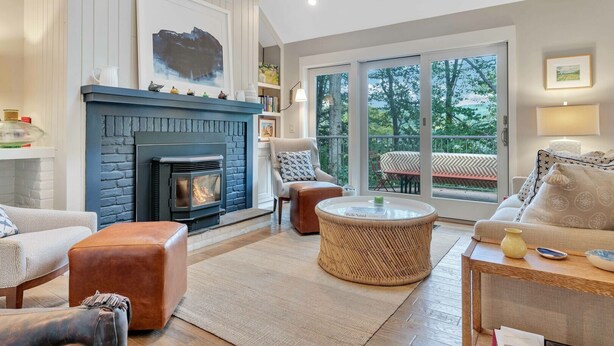 A living room with a fireplace, a sofa, a round coffee table, and a view of the outdoors. - Condo with Hot Tub & Private Sauna, Deere Run (Quechee)