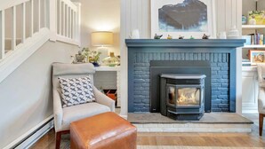 A living room with a fireplace, a staircase, and a bookshelf. - Condo with Hot Tub & Private Sauna, Deere Run (Quechee)