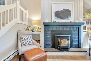 A living room with a fireplace, a staircase, and a bookshelf.