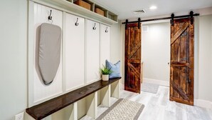 Un couloir avec un banc, un porte-manteau et une porte coulissante de style rustique.