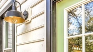 Une porte verte avec une fenêtre, un luminaire fixé au mur et une serrure à clavier.
