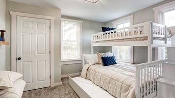A bedroom with a bunk bed, a door, and a window.