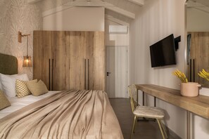 A bedroom with a wooden wardrobe, a bed with a beige blanket, a bedside table with a vase of flowers, and a television mounted on the wall. - Tsilivi Pandessia Villa with private pool (Planos)