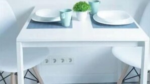 Un tavolo da pranzo con due piatti, una piccola pianta e una tazza. Sono presenti due sedie e due quadri appesi al muro.