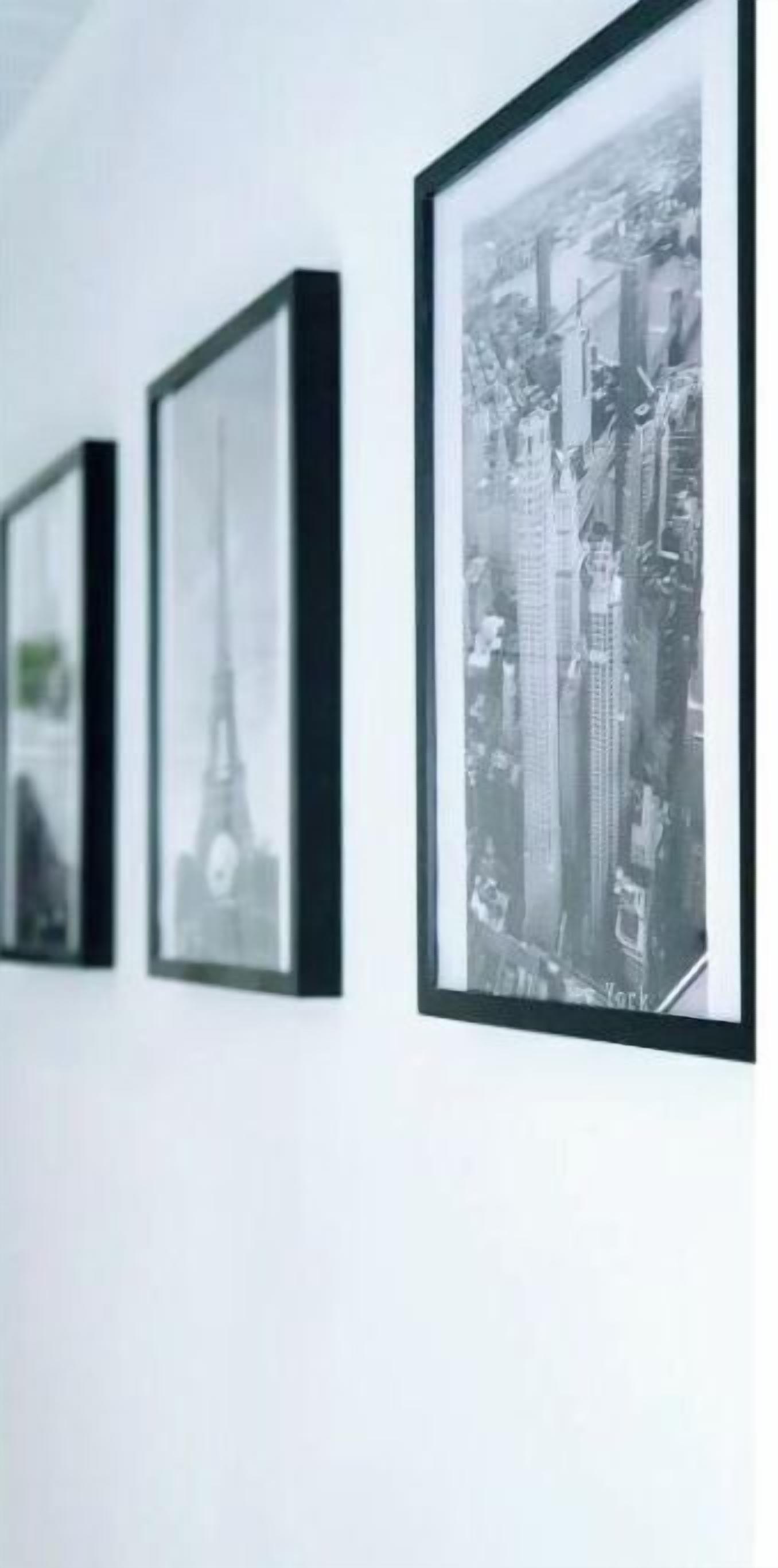 A wall with three framed black and white photographs of cityscapes.