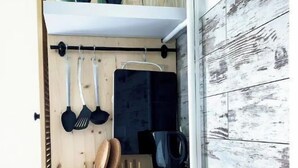 Una cucina compatta con mobili in legno, una macchina da caffè e utensili pensili.