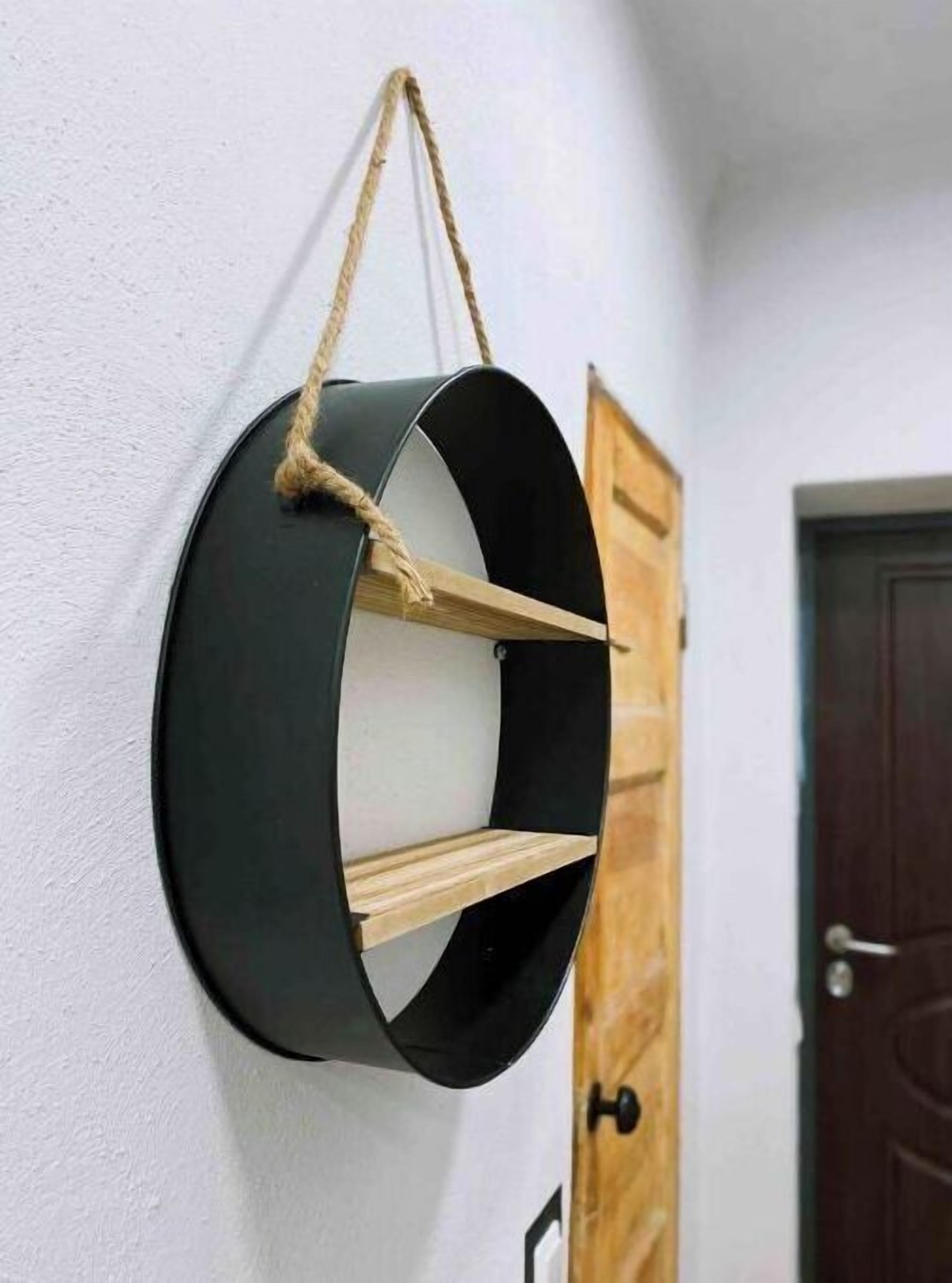 Une étagère circulaire à fixer au mur, dotée d’une poignée en corde, d’étagères en bois et d’un fond foncé.