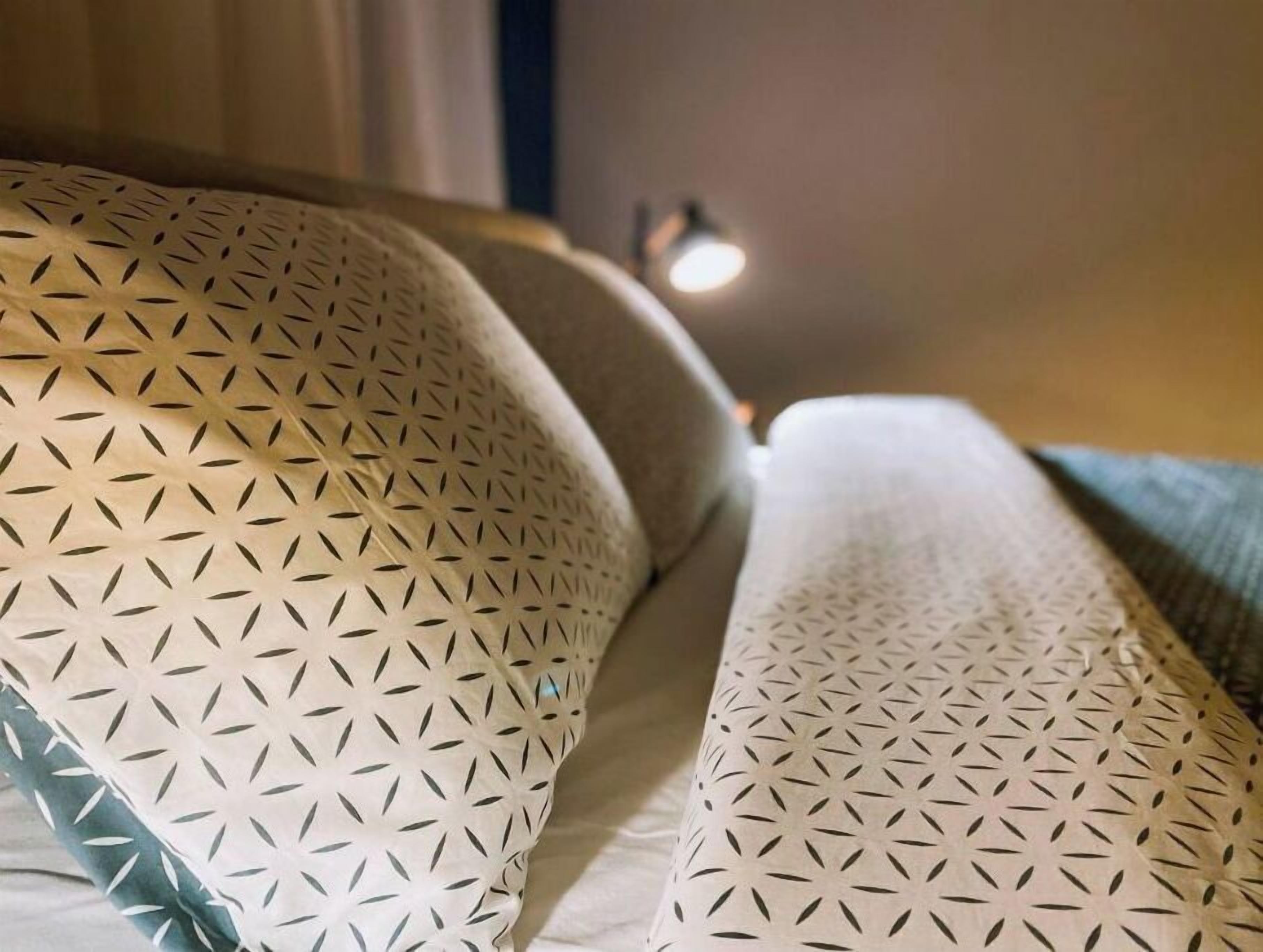 A bed with patterned pillows and a textured blanket.