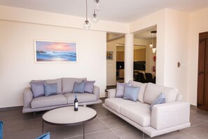 A living room with two sofas, a coffee table, and a painting of a sunset.