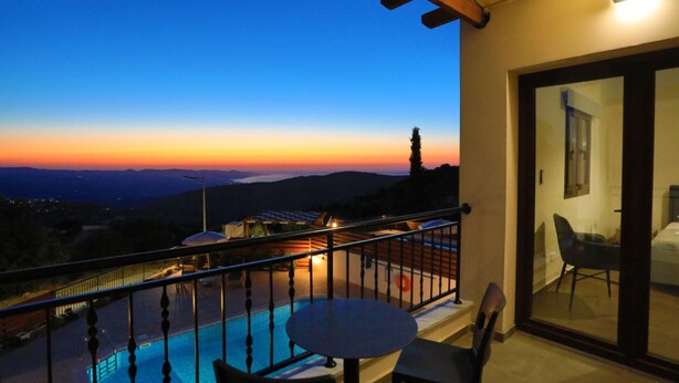 Ein Balkon mit Pool, Tisch und Stühlen, der Blick auf einen Sonnenuntergang bietet.