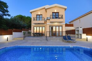 A two-story house with a swimming pool, outdoor seating, and a balcony.