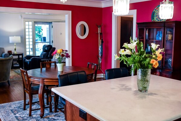 A dining area with a wooden table, chairs, and a vase of flowers.