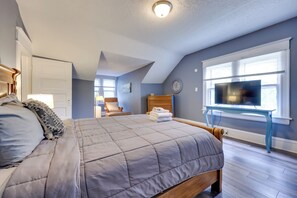 Ein Schlafzimmer mit einem Bett, einem Fernseher, einem Sessel und einem Fenster.