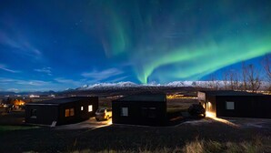 A remote cabin with a snow-covered mountain backdrop and the aurora borealis. - North Mountain View Suites (Akureyri)