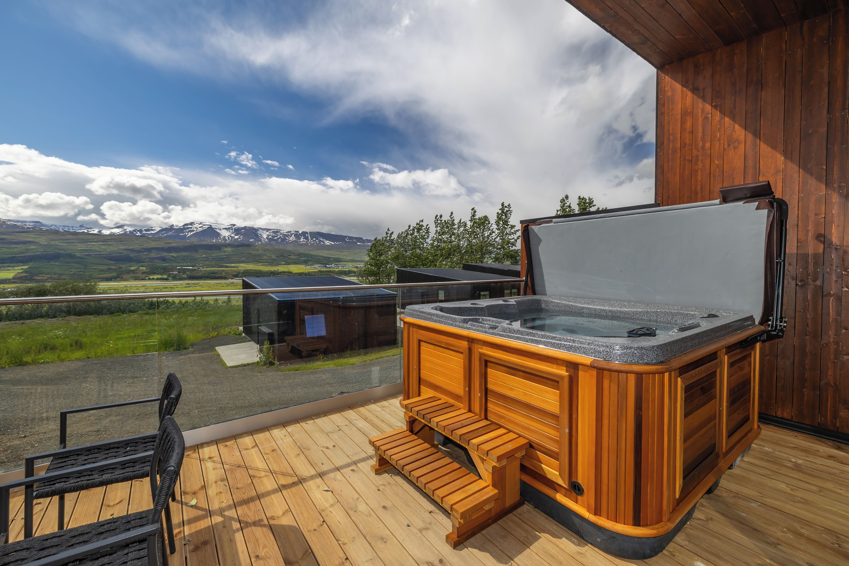 Une terrasse en bois avec un jacuzzi, une chaise et une vue sur les montagnes.