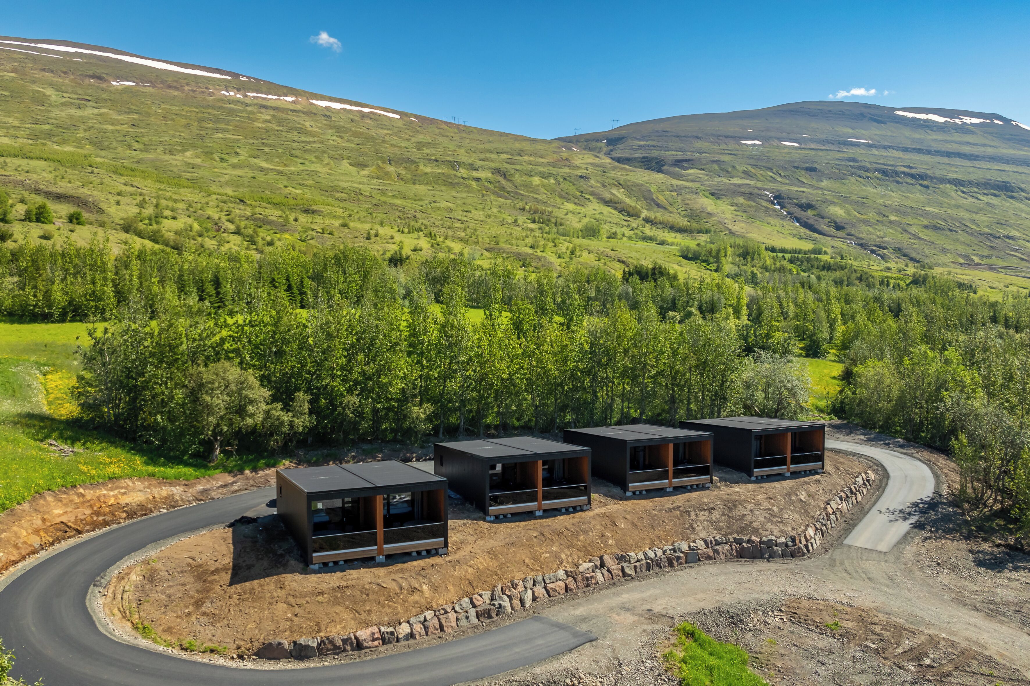 A modern building with a curved driveway and a view of a mountainous landscape.