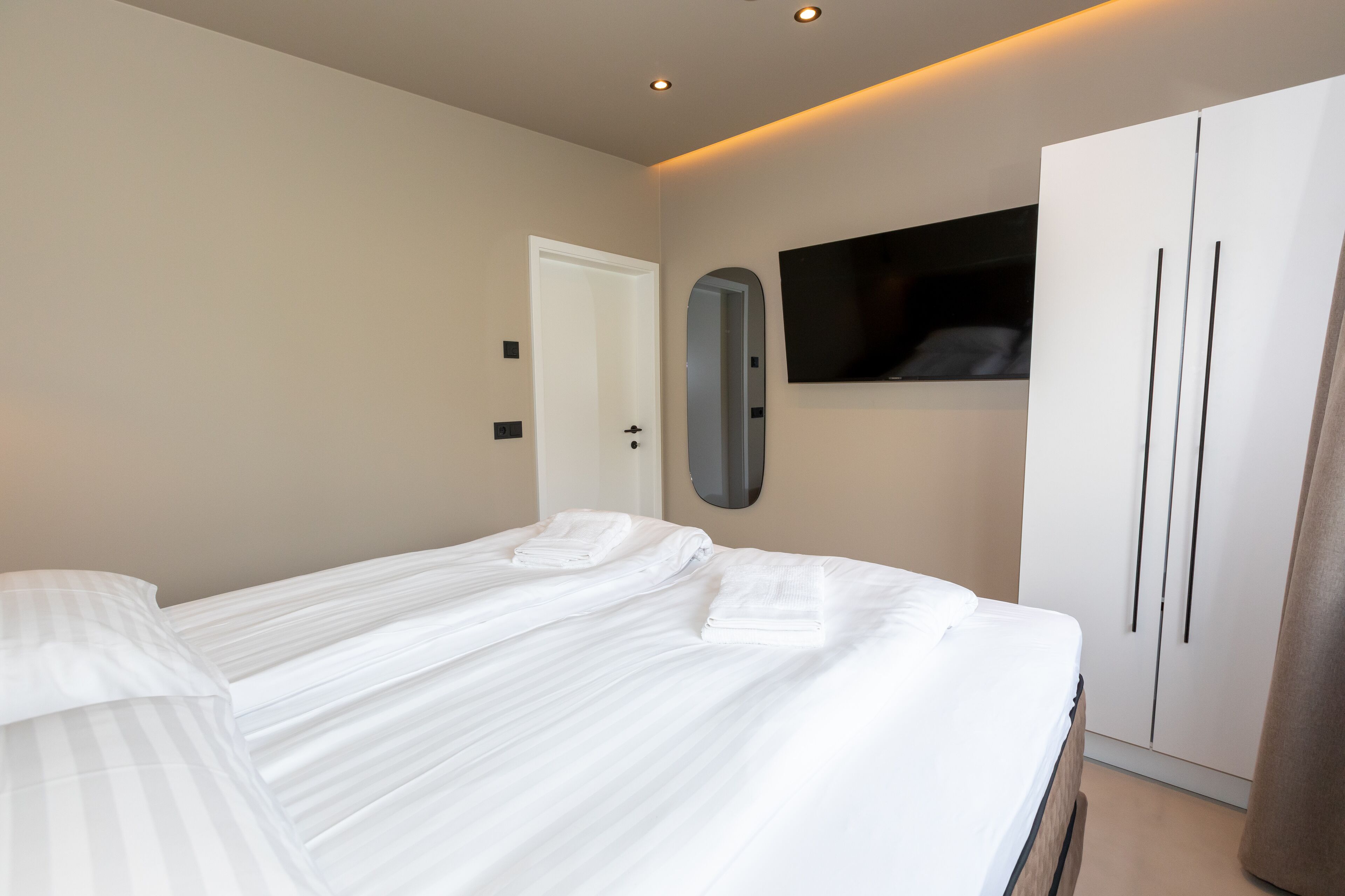 Una habitación de hotel con cama, armario, espejo y televisor.
