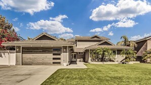 A modern two-story house with a garage, a well-maintained lawn, and a clear blue sky.