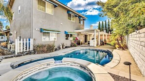 A house with a swimming pool, a patio, and a small outdoor kitchen.