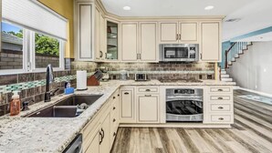 A kitchen with beige cabinets, a stainless steel microwave, a dishwasher, and a granite countertop.