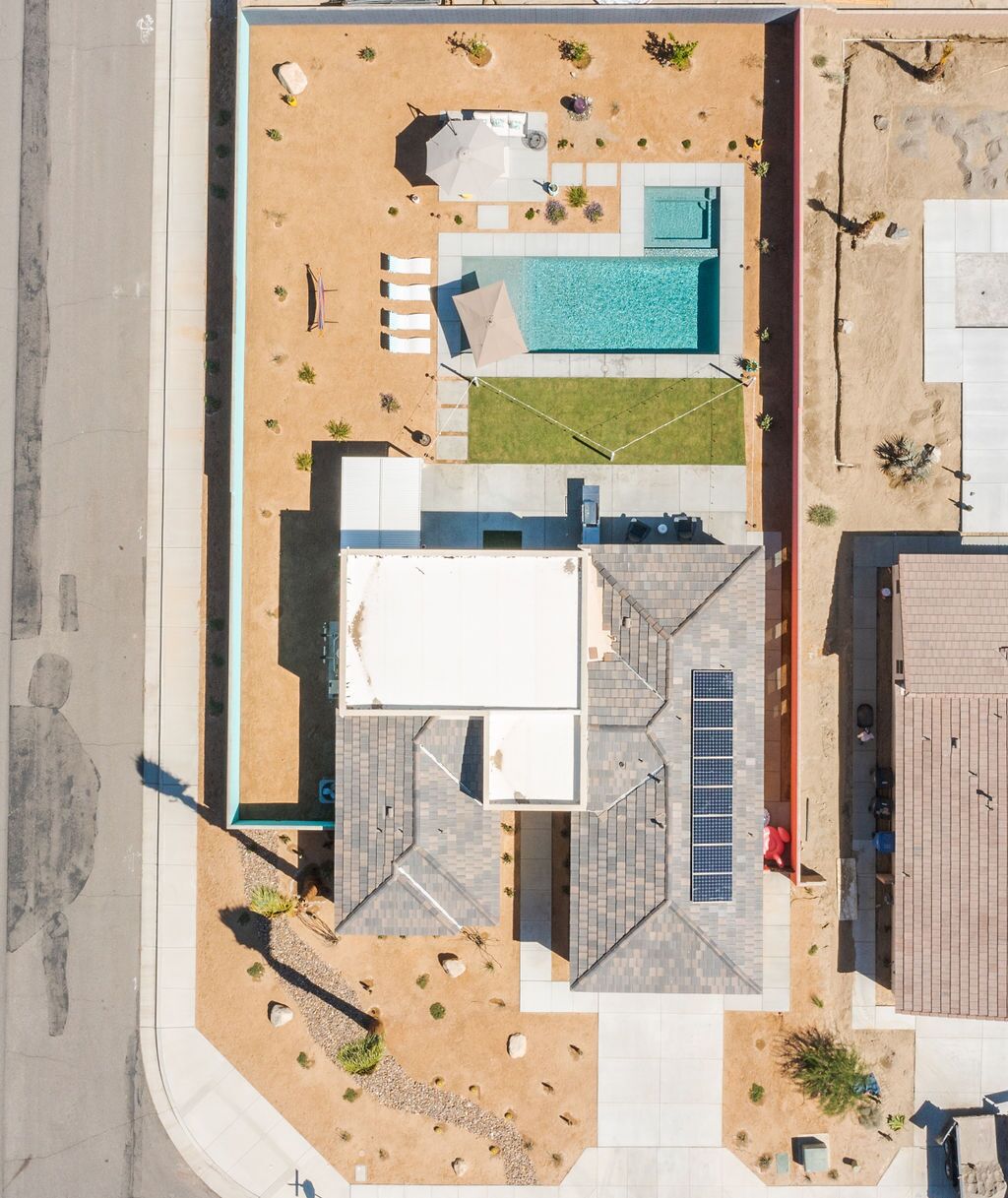 An aerial view of a property with a swimming pool, outdoor seating, and a covered patio area.