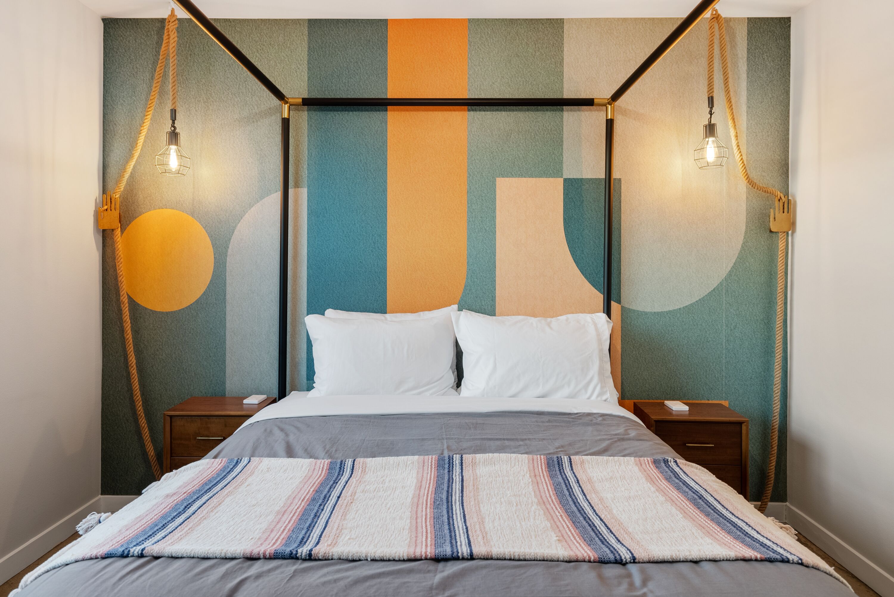 A modern hotel room with a bed, two bedside tables, and a unique wall design.