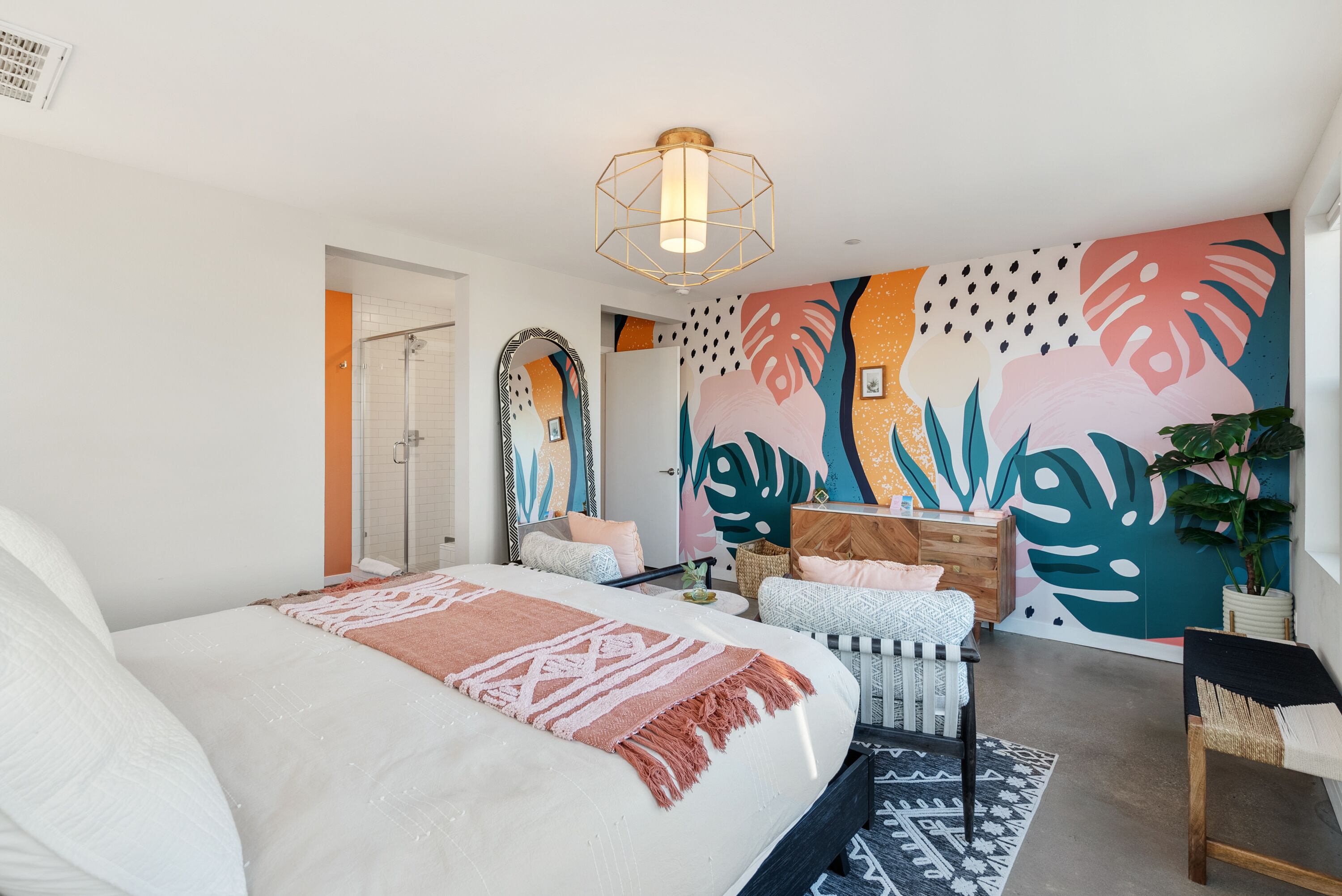 Un dormitorio moderno con una cama grande, un mural en la pared, un cabecero de madera y una lámpara en el techo.
