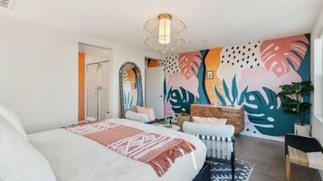 Un dormitorio moderno con una cama grande, un mural en la pared, un cabecero de madera y una lámpara en el techo.