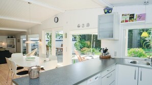 Eine moderne Küche mit weißen Schränken, einer Arbeitsplatte aus Granit und Blick auf den Garten.