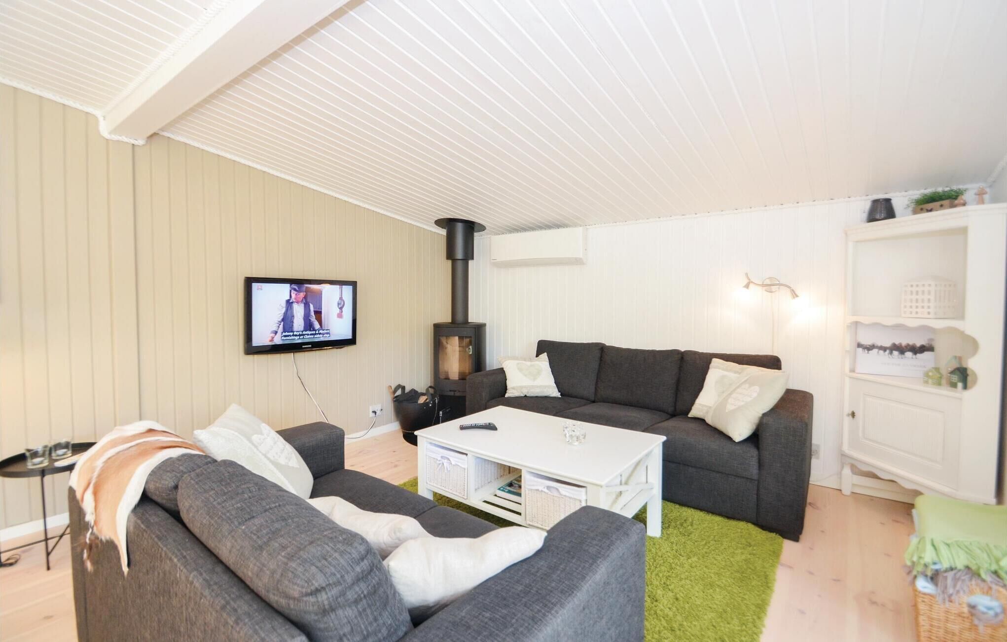 Ein gemütliches Wohnzimmer mit einer Couch, einem Couchtisch und einem an der Wand montierten Fernseher.