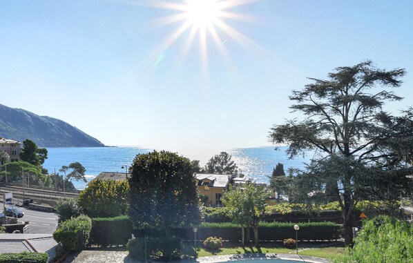 A residential area with a pool, a view of the sea, and a mountain in the background.