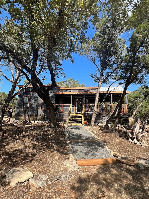 Un chalet rustique doté d’une terrasse en bois, entouré d’arbres.