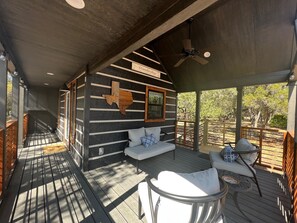 Eine Holzhütte mit geneigtem Dach und einer Veranda mit Sitzgelegenheiten.