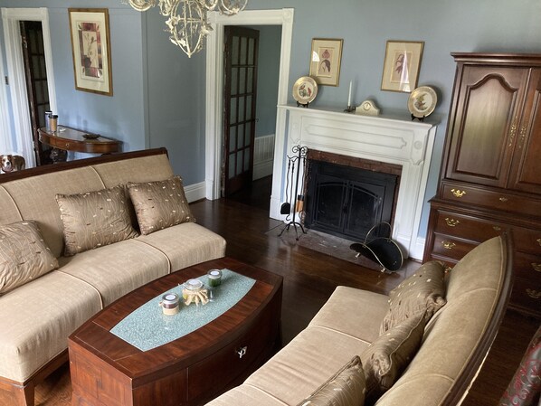A living room with a beige sofa, a wooden coffee table, a fireplace, and a cabinet.