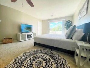 Relax in this serene bedroom with a large bed, TV, and a window offering a view.