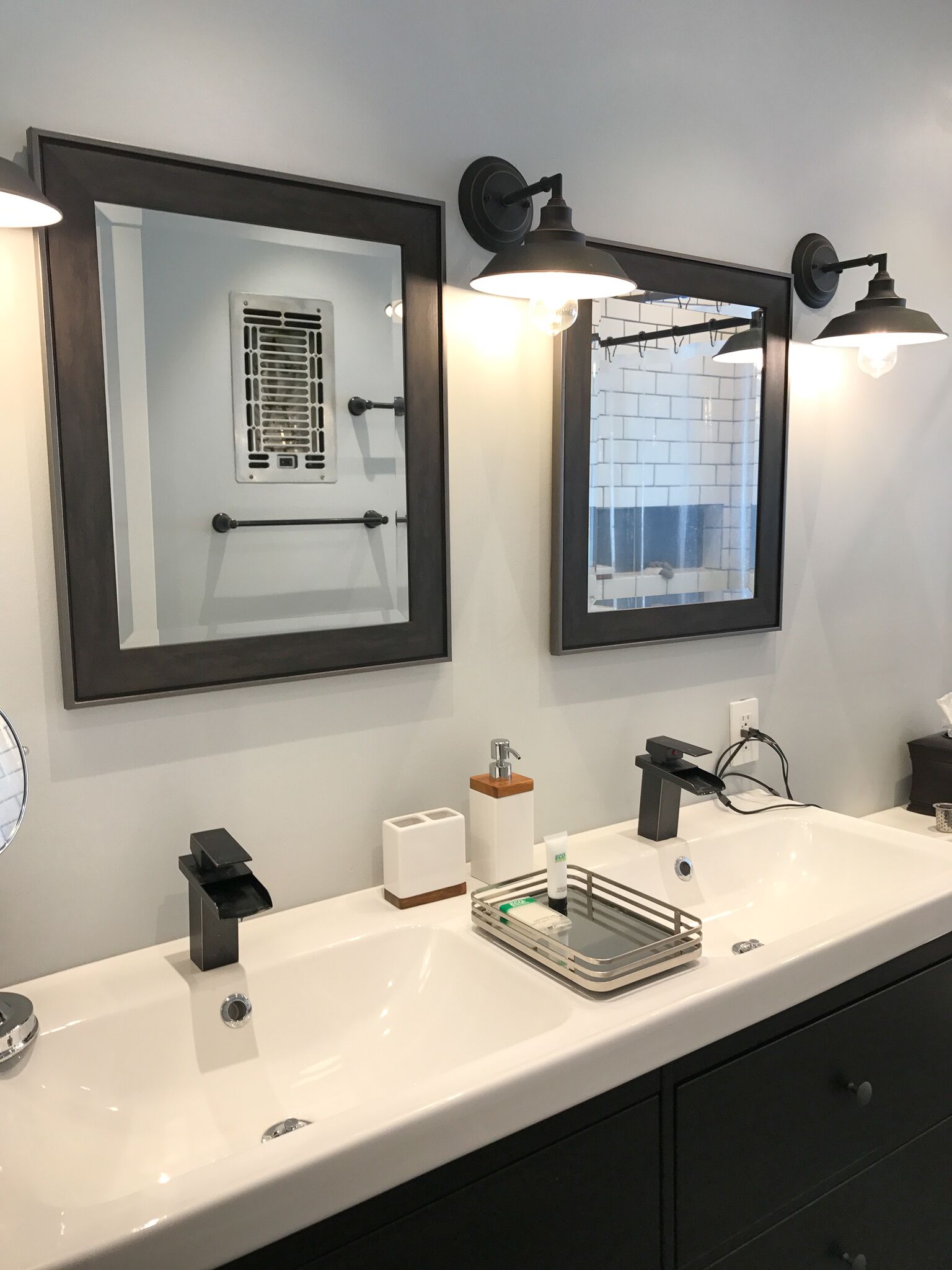 Une salle de bain moderne avec deux lavabos, un miroir et des luminaires fixés au mur.