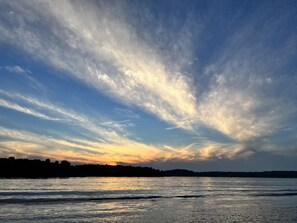 A sunset over a calm body of water with a silhouette of trees in the distance. - Two Cottages-On Island- Great for two families (Archipelago)