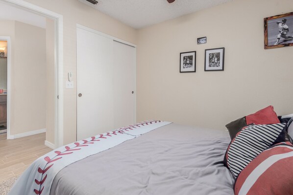 A bedroom with a bed, a door, and two framed pictures on the wall.