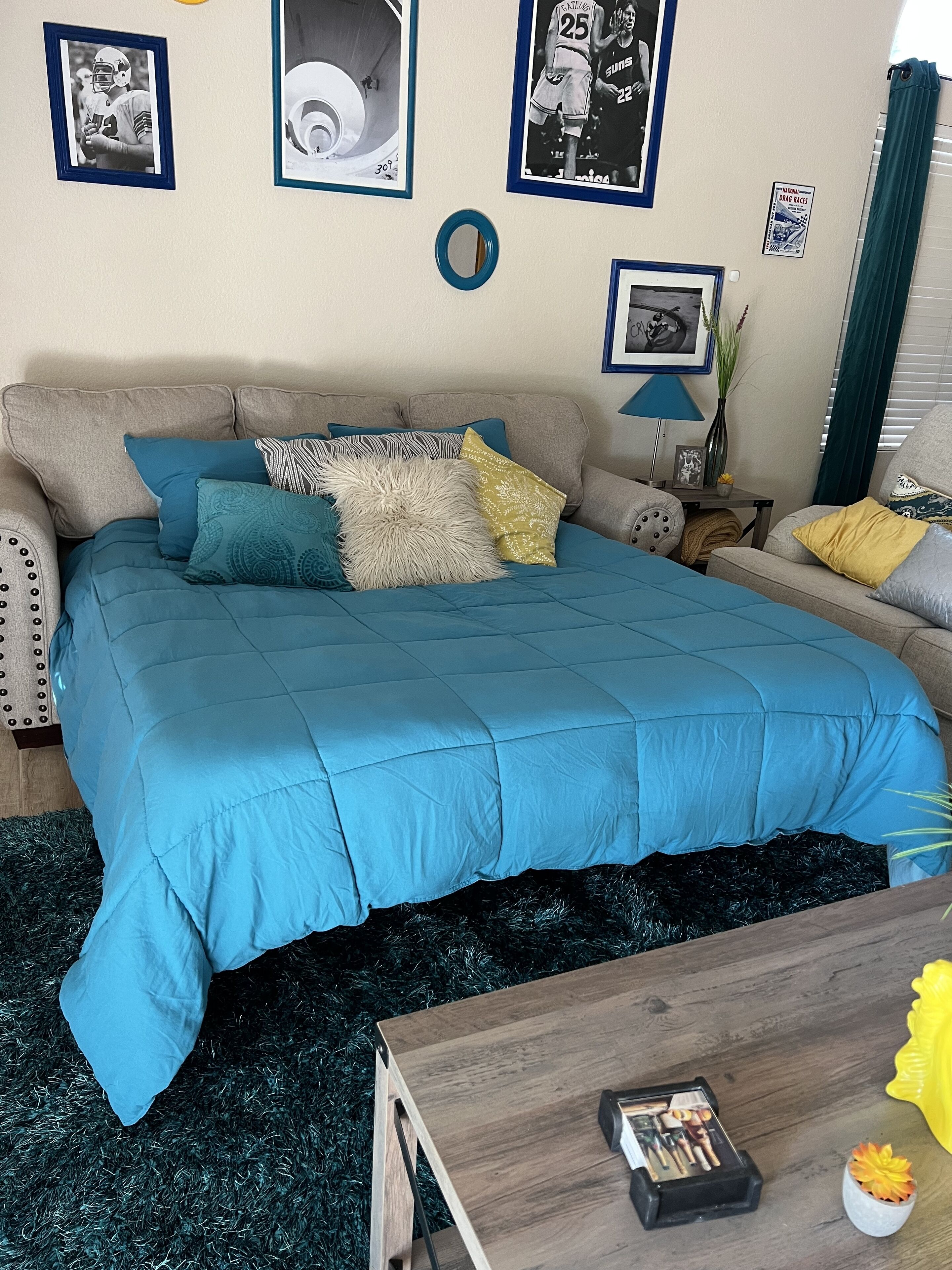 A bedroom with a bed, a wooden coffee table, a lamp, and a small plant.