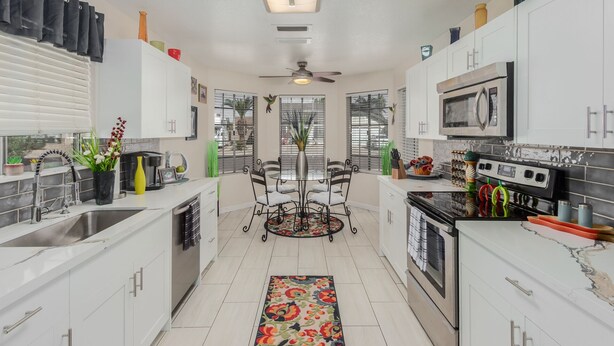 Una cocina moderna con armarios blancos, una isla central y un comedor.