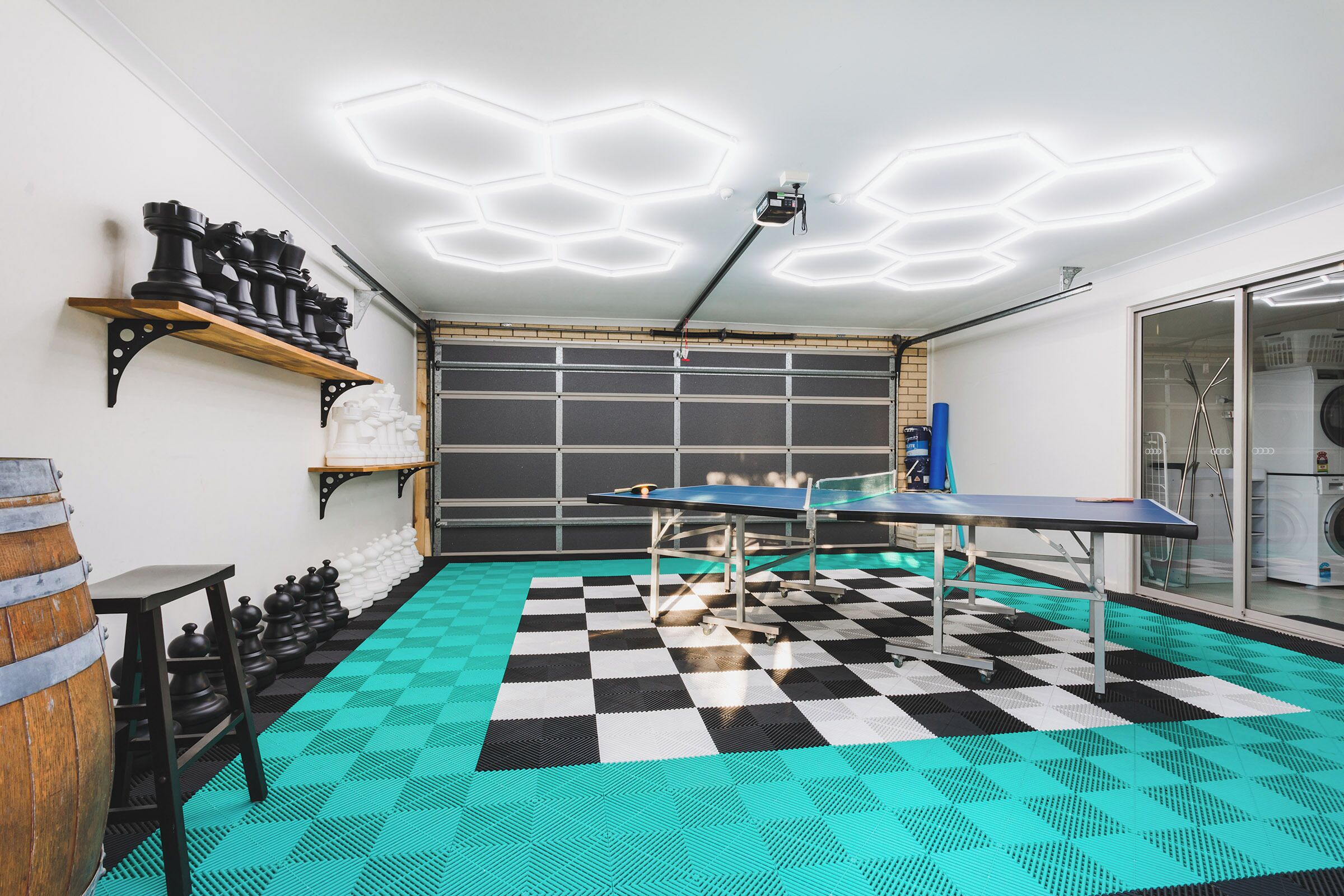 A room with a checkered floor, a ping pong table, a chessboard, and a ping pong table.