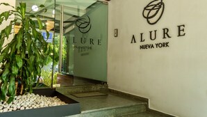 Una entrada moderna con puerta de cristal, un logotipo y el nombre 'ALURE Nueva York' en la pared.