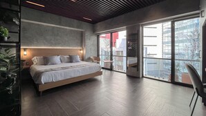 Un dormitorio moderno con una cama grande, techo de madera y vista de la ciudad a través de amplios ventanales.