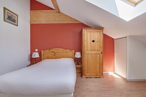 A bedroom with a wooden bed, a wardrobe, and a skylight.