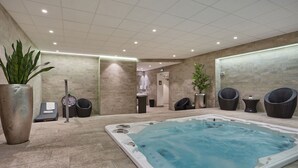 A spa area with a hot tub, seating, and a clock. - Studio 20m2 dans résidence avec services hôteliers (Paris)