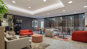 A modern interior with sofas, a coffee table, and a decorative mirror. - Studio 20m2 dans résidence avec services hôteliers (Paris)