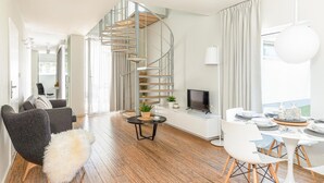 Een moderne woonkamer met een spiltrap, een eethoek en een televisie.