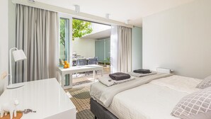 Een moderne hotelkamer met een groot bed, een bureau en uitzicht op een terras.