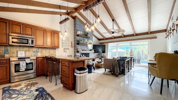 Une cuisine spacieuse avec des meubles en bois, un grand îlot central et un coin repas agrémenté d’une chaise jaune.