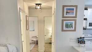 Eine moderne Küche mit weißen Schränken und einem eingebauten Backofen. Der Boden ist mit Holz im Fischgrätmuster ausgelegt, und ein weißer Teppich führt in einen Essbereich mit Tisch und Stühlen.
